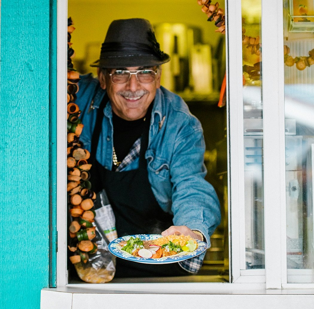 A food vendor holds out a plate of fresh Mexican food at the Olympia Farmers Market
